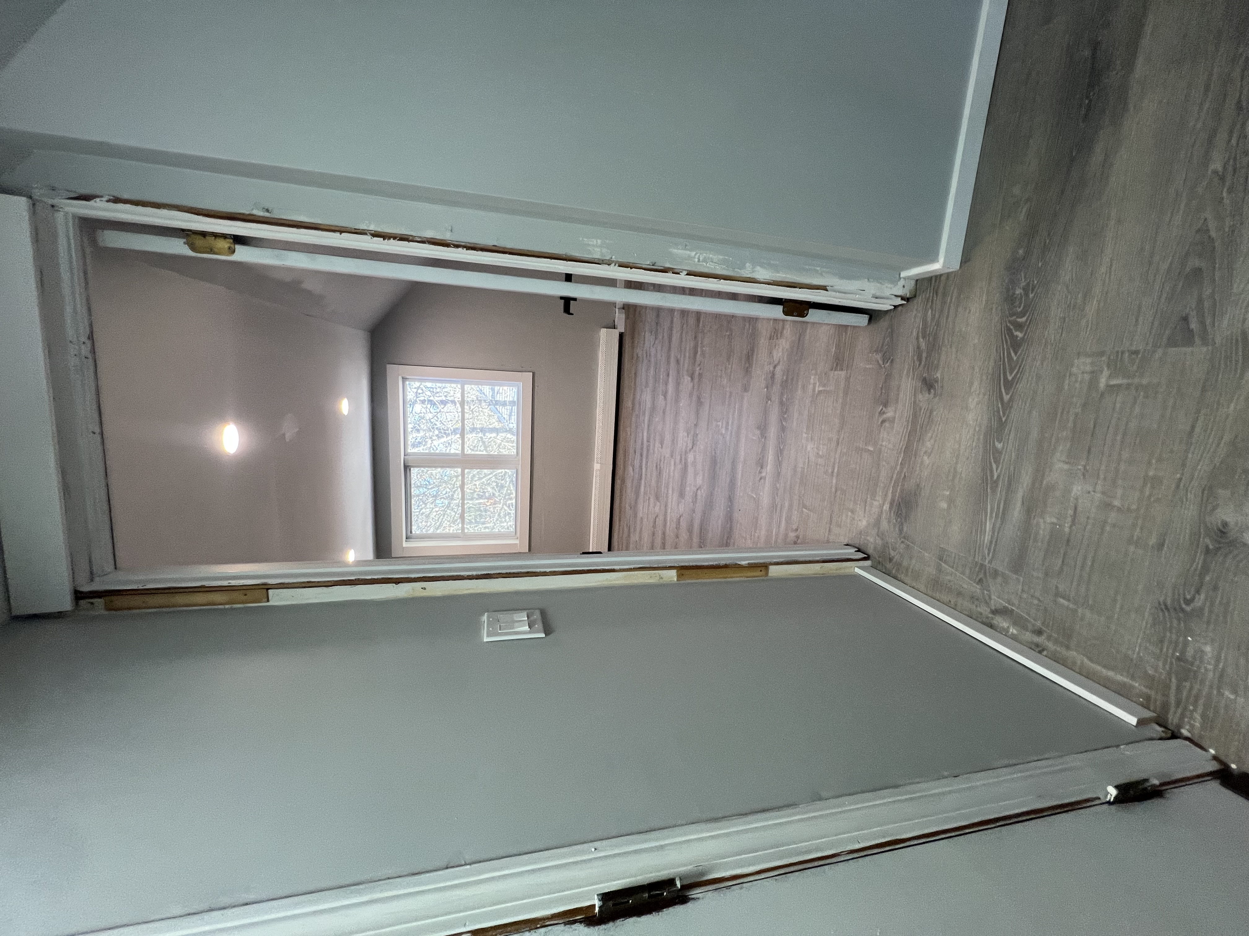Finished upstairs room with gray flooring, white trim, and recessed lights.